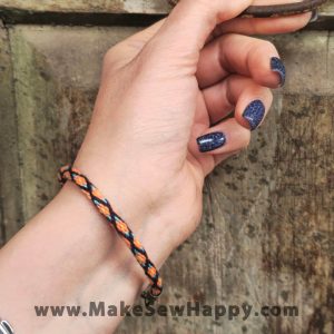 دستبند نخی طرح ضربدر رنگ مشکی و نارنجی و آبی روشن