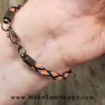 دستبند نخی طرح ضربدر رنگ مشکی و نارنجی و آبی روشن