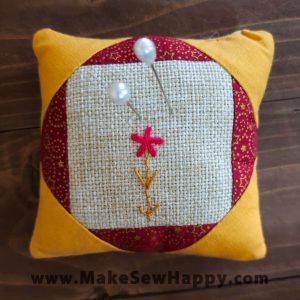 جا سوزنی پارچه‌ای طرح گل‌دوزی آبستره رنگ سفید و قرمز و زرد با گل قرمز