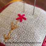 جا سوزنی پارچه‌ای طرح گل‌دوزی آبستره رنگ سفید و قرمز و زرد با گل قرمز