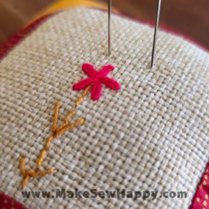 جا سوزنی پارچه‌ای طرح گل‌دوزی آبستره رنگ سفید و قرمز و زرد با گل قرمز